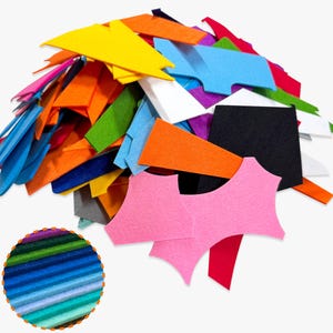 Puede incluir: Un montón de piezas de fieltro de colores en varias formas y tamaños. El fieltro es en tonos de amarillo, naranja, azul, verde, rosa, rojo, negro y blanco. Una incrustación circular muestra un degradado de fieltro azul y verde.