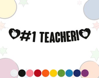 May include: A black banner with the text "#1 TEACHER!" in bold letters. The banner features a heart-shaped design with an apple in the center on each end. A colorful garland of felt circles is at the bottom.