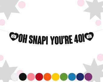 May include: Black and white banner with the text "OH SNAP! YOU'RE 40!" and a camera icon in a heart shape on each end.