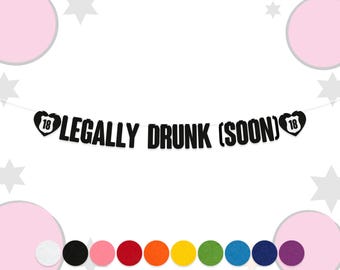 May include: A black banner with the text "LEGALLY DRUNK (SOON)" in bold, capital letters. The banner has a heart shape with the number "18" on each end. The banner is strung between two heart shapes. A row of colorful felt circles is at the bottom.