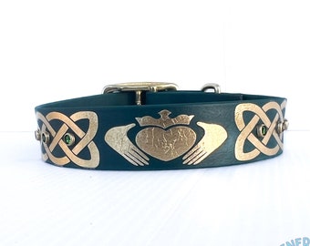 May include: A dark green leather dog collar with gold Celtic knot designs and green gemstones. The collar features a gold heart with a crown and two hands.