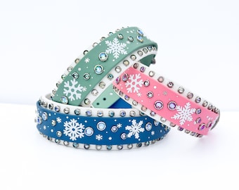 May include: Three dog collars with snowflake designs and rhinestones. The collars are in shades of green, pink, and blue.
