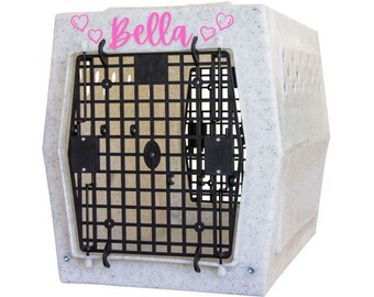 May include: A light gray speckled pet crate featuring a black grid door and the name Bella printed in pink script font, flanked by four small pink heart outlines on the top front edge of the plastic enclosure for animal containment.