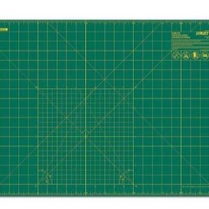 May include: Green self-healing cutting mat with a grid pattern and ruler markings. The mat is designed for use with craft knives and other cutting tools.