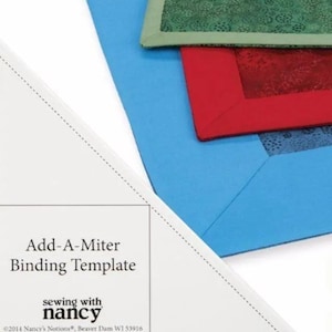 May include: A white Add-A-Miter Binding Template with text and blue, red, and green fabric samples. The template is from Nancy's Notions, made in the USA. The fabric samples have a mitered corner design.