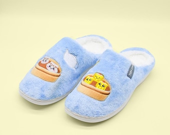 May include: A pair of light blue plush slippers featuring white faux fur lining and embroidered food graphics on the top. One slipper displays a tan bamboo steamer with two round dumplings, while the other shows three yellow rectangular dim sum pieces.