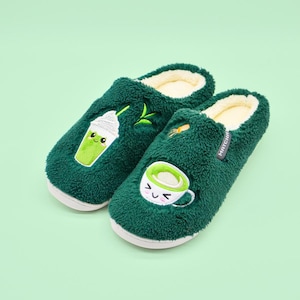 May include: A pair of green fuzzy slippers with embroidered matcha latte and matcha milkshake designs. The slippers have a white inner lining and the text "MATCHA" is embroidered on one slipper.