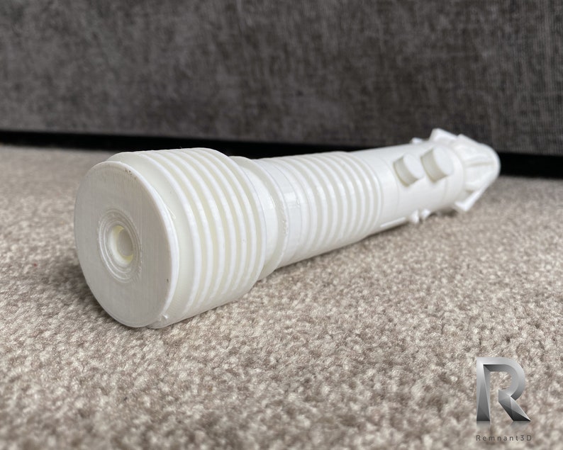 May include: White 3D printed prop resembling a futuristic weapon with a textured barrel and two buttons on the side.