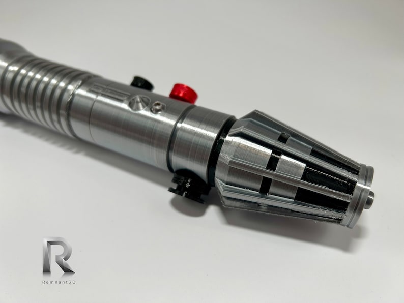 May include: A silver lightsaber with black and red accents. The lightsaber has a textured surface and a black and silver emitter.