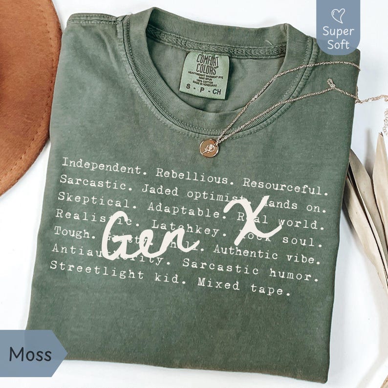 Moss green Comfort Colors Gen X humor t-shirt featuring satirical and sarcastic Gen X traits in a typewriter-style font with handwritten “Gen X” script overlay. Made from 100% ring-spun cotton, garment-dyed for a lived-in softness, and pre-shrunk for lasting comfort. Shown folded flat with a gold necklace and earthy accents for a cozy, nostalgic feel. Perfect for Generation X adults who love sarcastic humor, retro 80s 90s nostalgia, and authentic, laid-back style. Great funny Gen X gift idea.