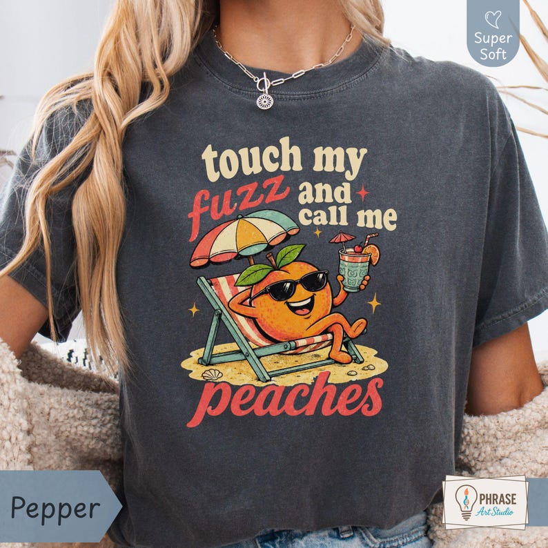 Pepper charcoal grey-colored Comfort Colors shirt styled on a model, featuring a bold 90s cartoon peach graphic reading 'touch my fuzz and call me peaches' for an unhinged dark humor vibe. Designed by experts at PhraseArtStudio - to solve the problem of finding a truly shocking white elephant gift.