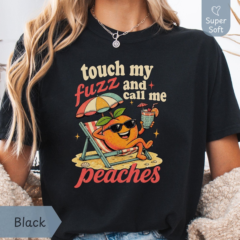 Black classic-colored Comfort Colors shirt featuring a high-contrast vintage cartoon peach on a beach towel reading 'touch my fuzz and call me peaches' for a shirts that go hard aesthetic. Designed by experts at PhraseArtStudio - to solve the problem of standing out at an adult dirty joke gift exchange.