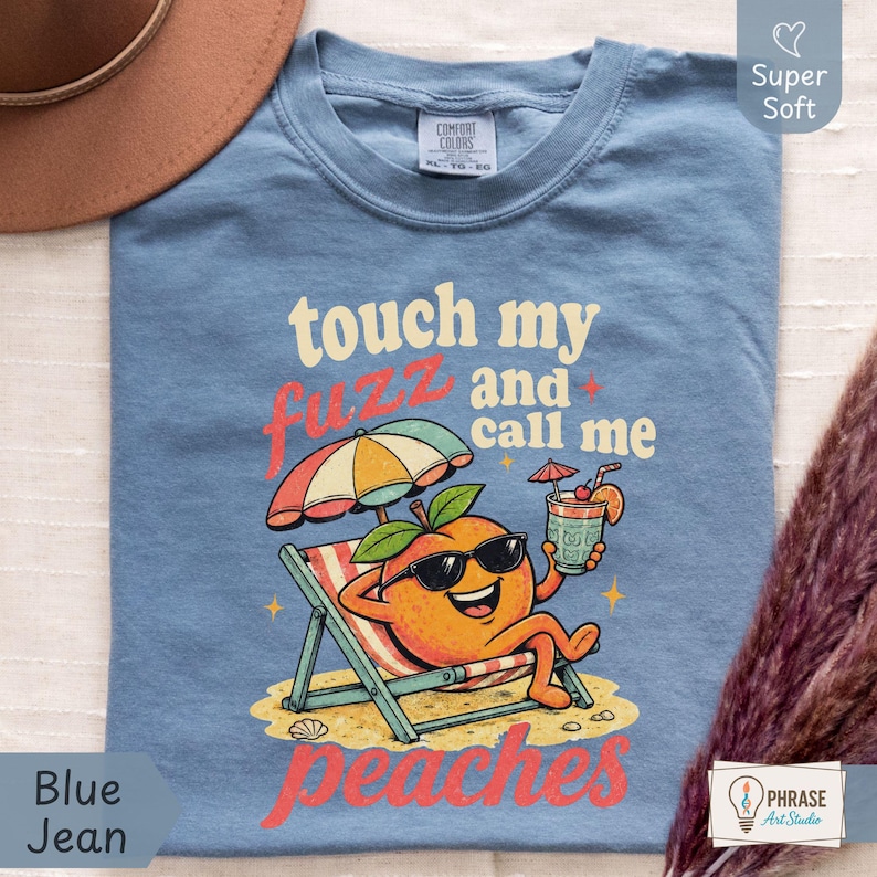 Blue Jean denim-colored Comfort Colors shirt featuring a detailed vintage cartoon peach holding a summer drink reading 'touch my fuzz and call me peaches' for an edgy streetwear vibe. Designed by experts at PhraseArtStudio - to solve the problem of boring, plain text adult joke shirts.