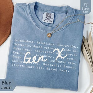 Blue Jean Comfort Colors Gen X humor t-shirt featuring satirical and sarcastic Gen X traits in a typewriter font with handwritten “Gen X” script. Made from 100% ring-spun cotton, garment-dyed for a soft, vintage feel, and pre-shrunk for lasting comfort. Styled flat lay with a gold necklace and neutral accents. Perfect for Generation X adults who love nostalgic 80s 90s humor, sarcasm, and classic retro vibes. Ideal funny Gen X gift or everyday tee with authentic laid-back attitude.
