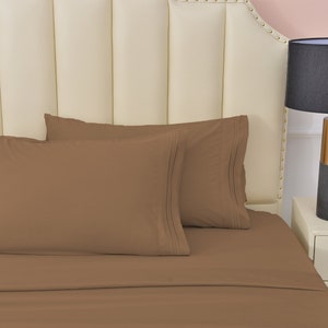 May include: Two brown pillowcases with a white headboard in the background. The pillowcases have a subtle pleat detail.