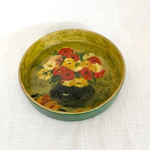 Puede incluir: Un cuenco de madera redondo de color verde y amarillo con una imagen pintada de un ramo de flores rojas, amarillas y blancas en un jarrón negro.