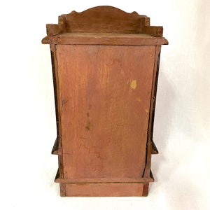 May include: A wooden cabinet with a dark brown finish and a simple design. The cabinet has three shelves and a small top shelf. The back of the cabinet is visible in the image.