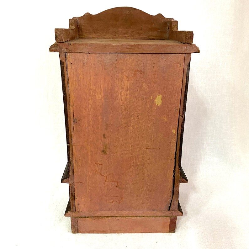 May include: A wooden cabinet with a dark brown finish and a simple design. The cabinet has three shelves and a small top shelf. The back of the cabinet is visible in the image.