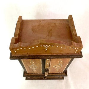 May include: A small wooden cabinet with two doors and a drawer. The cabinet is decorated with intricate inlaid designs of mother-of-pearl.