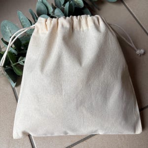 May include: A plain white cotton drawstring bag with a white cord.