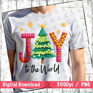 May include: A light gray t-shirt featuring the word "JOY" with a Christmas tree and snowflakes. The letter "J" is orange and pink, the "O" is a Christmas tree, and the "Y" is leopard print. The text "to the World" is below.