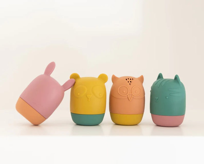 K&ouml;nnte beinhalten: Vier bunte Silikon-Badetiere in Tierform: ein rosa Kaninchen, ein gelber B&auml;r, eine orange Eule und eine gr&uuml;ne Katze. Jedes Spielzeug hat einen anderen Gesichtsausdruck und Merkmale.
