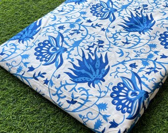 May include: White fabric with a blue floral pattern. The fabric has a traditional design with intricate details.