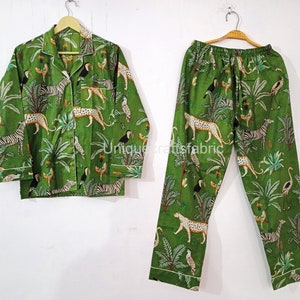 Puede incluir: Conjunto de pijama verde con estampado de jungla con cebras, tucanes y leopardos. La parte superior tiene un frente abotonado y mangas largas. Los pantalones tienen una cintura elástica.