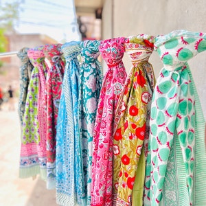 Könnte beinhalten: Eine Sammlung bunter Schals mit floralen und geometrischen Mustern. Die Schals sind aus Baumwolle und perfekt, um jedem Outfit einen Hauch von Farbe zu verleihen.