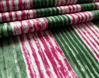 May include: Close-up of a fabric with alternating stripes of pink and green. The fabric is folded and the stripes are slightly blurred.