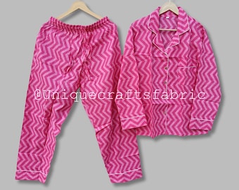 May include: Pink pajama set with a chevron pattern. The top has long sleeves and a collar. The pants have an elastic waistband.