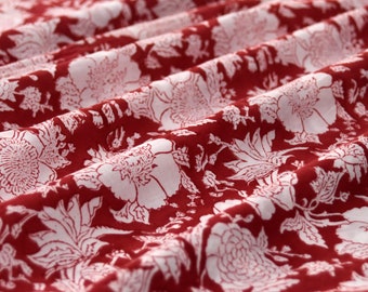 Pode incluir: Tecido vermelho com um padrão floral branco. O tecido está dobrado e o padrão é visível em ambos os lados da dobra.