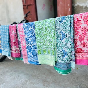 Pu&ograve; includere: Una collezione di pannelli di tessuto colorati con motivi floreali. I pannelli sono appesi a uno stendino e sono in cotone. I pannelli sono in varie tonalit&agrave; di blu, verde, rosa e giallo.