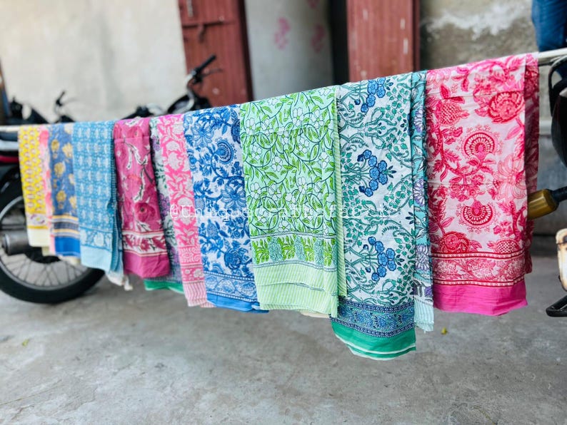 Pu&ograve; includere: Una collezione di pannelli di tessuto colorati con motivi floreali. I pannelli sono appesi a uno stendino e sono in cotone. I pannelli sono in varie tonalit&agrave; di blu, verde, rosa e giallo.