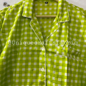 Peut inclure: Une chemise boutonn&eacute;e &agrave; carreaux verts et blancs avec une bordure blanche autour du col et des poches. La chemise a une fermeture boutonn&eacute;e et une &eacute;tiquette de taille indiquant "M".