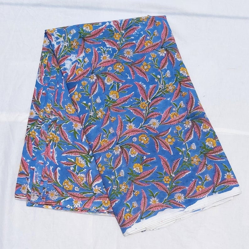 Peut inclure: Un tissu bleu avec un imprim&eacute; floral en rose, jaune et vert. Le tissu est pli&eacute; et a une bordure blanche.