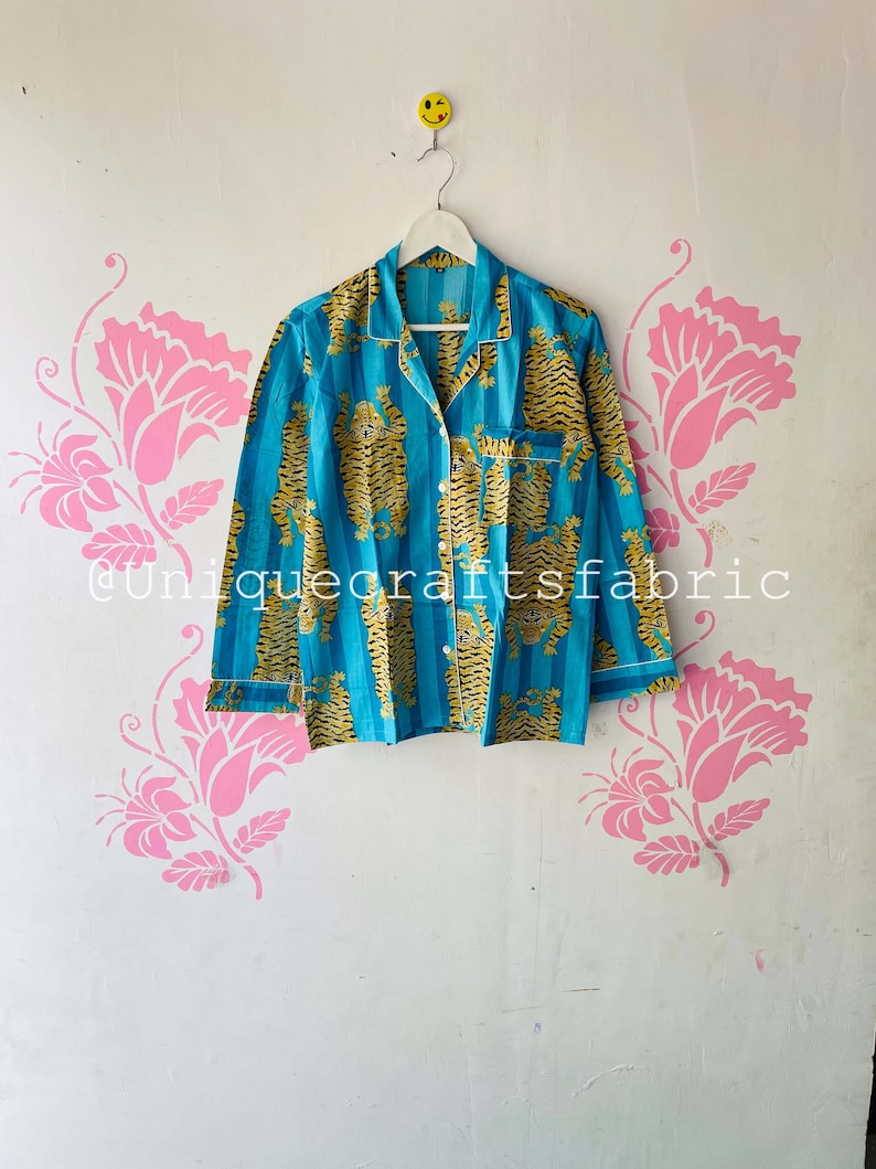 以下が含まれることがあります： 虎柄の青と黄色のストライプの部屋着の上着。襟と長袖です。