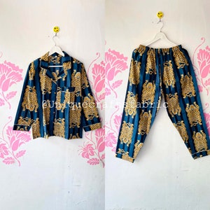 以下が含まれることがあります： 虎柄の青と金のストライプの部屋着セット。トップスはボタン留めと長袖。パンツはゴムウエストです。