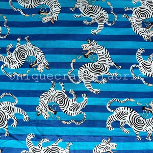 May include: White and black striped fabric with a repeating pattern of stylized tigers on a blue background. The tigers are facing different directions and have a swirling pattern on their bodies.
