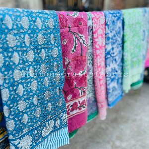 Pu&ograve; includere: Una collezione di sei sciarpe di cotone stampate a colori vivaci con motivi floreali. Le sciarpe sono appese a uno stendino.
