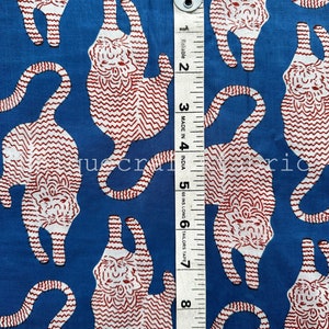 以下が含まれることがあります： 白と赤の虎が繰り返し描かれた青い布。布の右側に白いメジャーが置かれている。メジャーには「Reliable」と「Made in India」と書かれている。