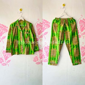 以下が含まれることがあります： 緑と金のストライプの虎柄のパジャマセット。トップはボタン留めと長袖。パンツはゴムウエストバンドです。