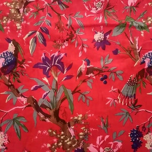 以下が含まれることがあります： スタイリッシュな鳥と花が描かれた花柄の赤い生地。背景は鮮やかな赤色で、花は紫、ピンク、白。鳥は青、黒、白です。