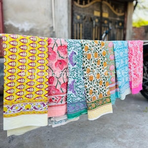 Pu&ograve; includere: Sei pannelli di tessuto con motivi diversi appesi a uno stendino. I pannelli sono di vari colori, tra cui giallo, rosa, verde, blu e bianco. I pannelli hanno disegni floreali e geometrici.