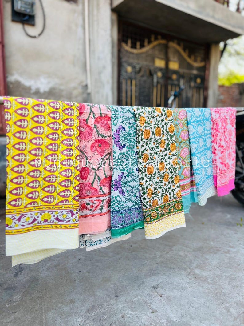 Pu&ograve; includere: Sei pannelli di tessuto con motivi diversi appesi a uno stendino. I pannelli sono di vari colori, tra cui giallo, rosa, verde, blu e bianco. I pannelli hanno disegni floreali e geometrici.