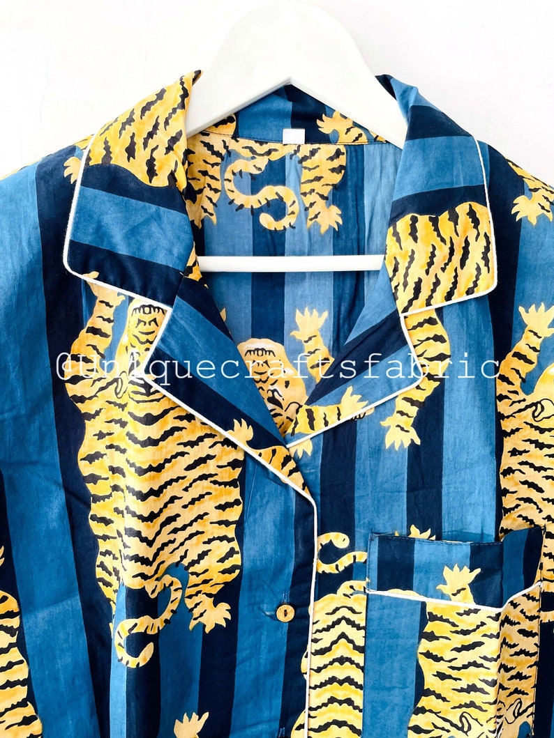 以下が含まれることがあります： 虎柄の青と白のストライプの寝巻きの上着。襟は白で、ボタン留めです。