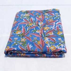 Peut inclure: Un tissu en coton bleu pli&eacute; avec un imprim&eacute; floral rose et jaune.