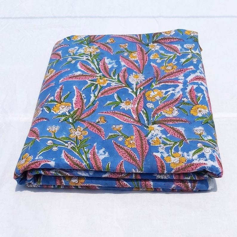 Peut inclure: Un tissu en coton bleu pli&eacute; avec un imprim&eacute; floral rose et jaune.