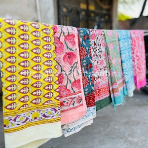 Pu&ograve; includere: Una collezione di sei quadrati di tessuto colorati con vari motivi floreali e geometrici. I tessuti sono appesi a una linea e sono fatti di cotone.