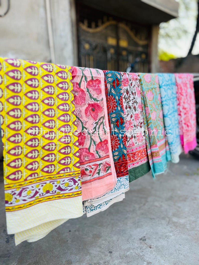 Pu&ograve; includere: Una collezione di sei quadrati di tessuto colorati con vari motivi floreali e geometrici. I tessuti sono appesi a una linea e sono fatti di cotone.